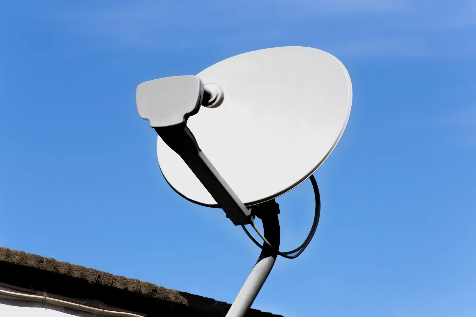 White satellite dish on a pole against a clear blue sky