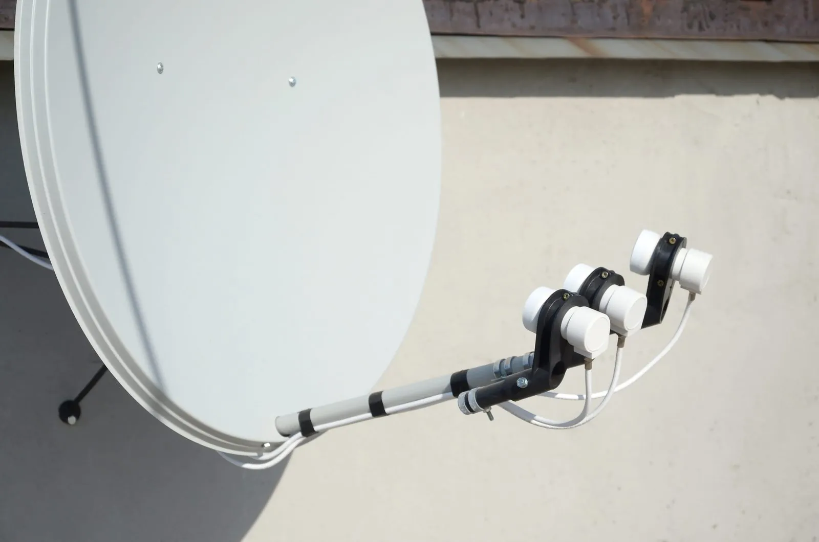 Close-up of a satellite dish arm carrying three LNBs